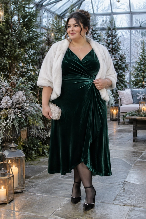 Emerald Velvet Occasion Outfit A deep green velvet dress is styled with a white cropped shrug, sheer black tights, black ankle-strap heels, and a metallic clutch.